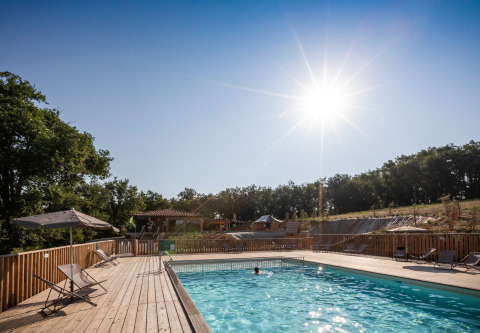 Día soleado junto a la piscina en Huttopia Pays de Cordes sur Ciel, parque vacacional en Occitania, Francia.