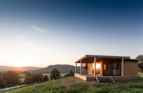 Chalet Evasion Vista, een houten blokhut op een heuvel bij zonsondergang met zicht op vallei en bergen.