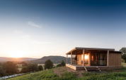Træhytte Chalet Evasion Vista på en bakkeskråning ved solnedgang med udsigt over dalen og bjergene.
