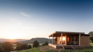 Chalet Evasion Vista, een houten blokhut op een heuvel bij zonsondergang met zicht op vallei en bergen.