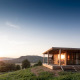 Træhytte Chalet Evasion Vista på en bakkeskråning ved solnedgang med udsigt over dalen og bjergene.