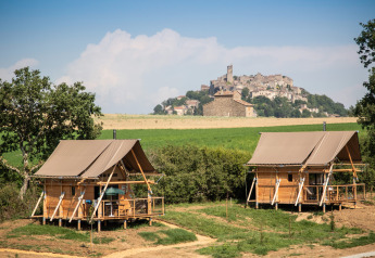Dos tiendas safari en Cahutte con vistas panorámicas a un pueblo medieval en la cima de una colina.