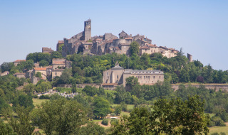 Vista de un pintoresco pueblo en lo alto de una colina cerca de Vindrac Alayrac, Occitania, Francia, rodeado de árboles.