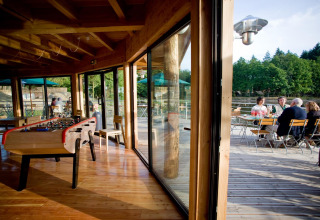 Binnen een tafelvoetbal en buiten een terras met gasten bij Village Huttopia Senonches in Frankrijk
