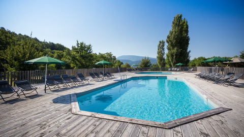 Piscina al aire libre con tumbonas y sombrillas en Village Huttopia Dieulefit, Auvergne-Rhône-Alpes, Francia.