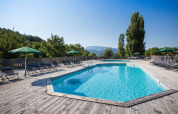 Swimmingpool med liggestole og parasoller, omgivet af træer på Village Huttopia Dieulefit i Auvergne-Rhône-Alpes.