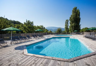 Swimmingpool med liggestole og parasoller, omgivet af træer på Village Huttopia Dieulefit i Auvergne-Rhône-Alpes.