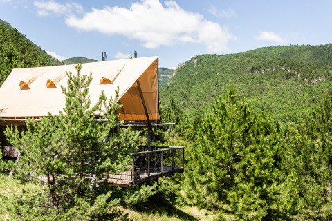 Lodge de lona con terraza entre pinos en Village Huttopia Dieulefit, Auvergne-Rhône-Alpes, Francia.