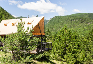 Teltlodge med terrasse i skovklædte bjerge ved Village Huttopia Dieulefit, Auvergne-Rhône-Alpes, Frankrig.