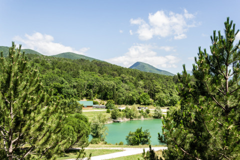 Vista panorámica de un parque vacacional verde con lago y montañas en Auvergne-Rhône-Alpes, Francia.