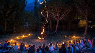 Niños observan un espectáculo de fuego al aire libre por la noche en el parque vacacional Huttopia Dieulefit, Francia.