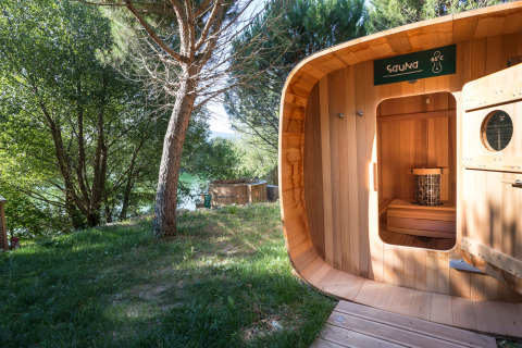 Sauna al aire libre de madera en Village Huttopia Dieulefit, rodeada de árboles en Auvergne-Rhône-Alpes, Francia.
