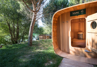 Outdoor wooden sauna at Village Huttopia Dieulefit, surrounded by green trees in Auvergne-Rhône-Alpes, France.