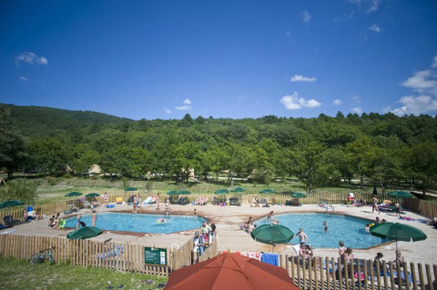 People relaxing around two swimming pools with parasols at Village Huttopia Dieulefit, Auvergne-Rhône-Alpes.