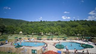 Personas disfrutando de dos piscinas y sombrillas en Village Huttopia Dieulefit, Auvergne-Rhône-Alpes, Francia.
