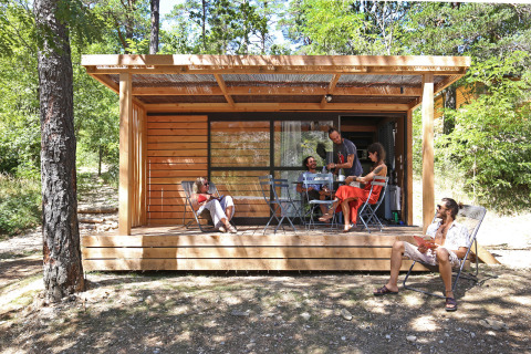 Cinco personas disfrutan en la terraza de Chalet Evasion, una cabaña moderna entre árboles.