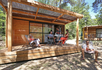 Cinque persone si rilassano sulla veranda in legno di uno Chalet Evasion al Camping d'Angers - Lac de Maine.