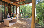 Familia disfrutando en la terraza de madera de Chalet Evasion, Camping d'Angers - Lac de Maine en Francia.