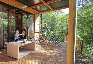 Familie entspannt auf der Holzterrasse eines Chalet Evasion im Camping d'Angers - Lac de Maine in Frankreich.