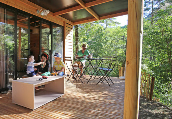 Familia disfrutando en la terraza de madera de Chalet Evasion, Camping d'Angers - Lac de Maine en Francia.