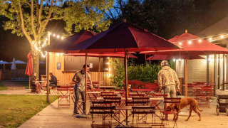 Zona de comedor al aire libre en Camping Valkenburg - Maastricht, Limburgo, Países Bajos, con invitados y perro.