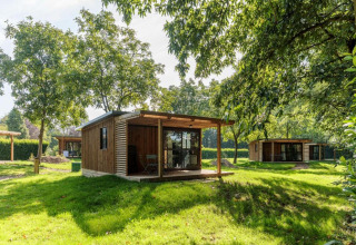 Bungalow in legno al Camping Valkenburg - Maastricht, parco vacanze nel Limburgo, Paesi Bassi, con alberi.