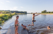 Børn leger og hopper i vandet fra en træbro ved en sø i Huttopia De Roos, Overijssel, Nederlandene.