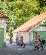 Familias pasean en bicicleta por el soleado parque vacacional Huttopia De Roos en Overijssel, Países Bajos.