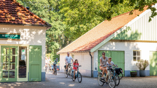 Familias pasean en bicicleta por el soleado parque vacacional Huttopia De Roos en Overijssel, Países Bajos.