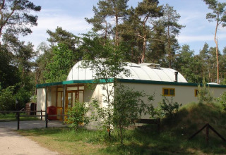 Camping Huttopia De Veluwe in Gelderland, Netherlands, modern holiday park building surrounded by trees.