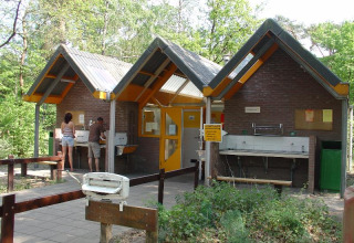 Edificio de servicio con lavabos y personas en Camping Huttopia De Veluwe, parque vacacional en Gelderland, Países Bajos.