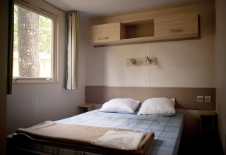 Interieur van een slaapkamer in een glamping mobile home cottage, met tweepersoonsbed en raam.