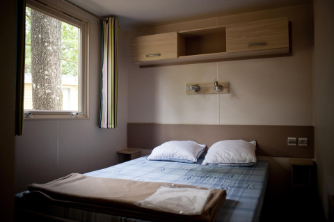Interieur van een slaapkamer in een glamping mobile home cottage, met tweepersoonsbed en raam.