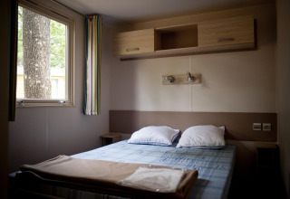 Vista interior de un dormitorio en una casa móvil de glamping, con cama doble y ventana.