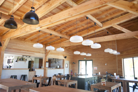 Lyse, træbeklædte spiseområde med moderne lamper i Village Huttopia Lanmary, Nouvelle-Aquitaine, Frankrig.