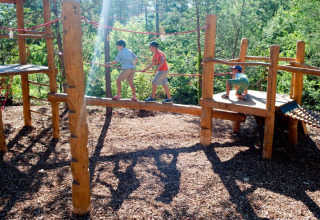 Børn leger på en trælegeplads i det fri i Village Huttopia Lanmary, feriepark i Nouvelle-Aquitaine, Frankrig.