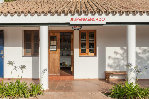 Entrance of a small supermarket with terracotta roof and white columns in Huttopia Parque de Doñana, Andalusia.