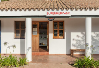 Entrance of a small supermarket with terracotta roof and white columns in Huttopia Parque de Doñana, Andalusia.