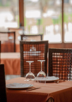 Mesa para dos personas en restaurante de Huttopia Parque de Doñana, Andalucía, España, con luz natural al fondo.