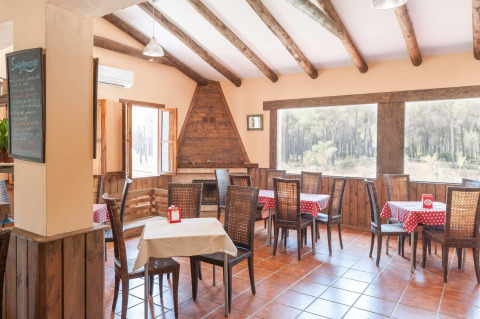 Bright, rustic dining room with wood beams and large windows at Huttopia Parque de Doñana, Andalusia, Spain.