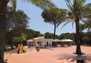 Spielplatz und Cafébereich bei Huttopia Parque de Doñana Ferienpark in Andalusien, Spanien bei Sonnenschein.