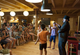 Magician performing for children and families in a wooden lodge at Village Huttopia Sud-Ardèche, France.