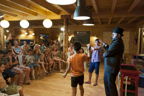 Magician performing for children and families in a wooden lodge at Village Huttopia Sud-Ardèche, France.