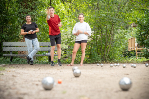Tres jóvenes juegan petanca en un parque verde en Village Huttopia Pays de Condrieu, Auvernia-Ródano-Alpes, Francia.