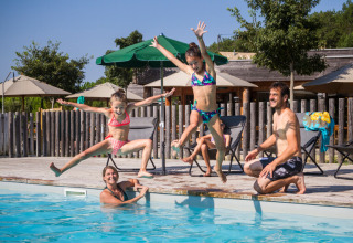 En familie nyder tid sammen ved poolen i Village Huttopia Pays de Condrieu, Auvergne-Rhône-Alpes, Frankrig.