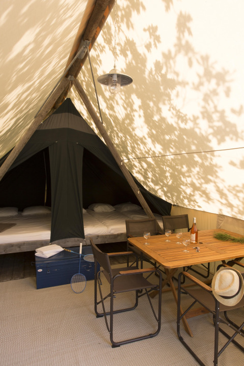 Intérieur d’une tente safari Canadienne à Village Huttopia Lac de Rillé, France, avec table et lits visibles.