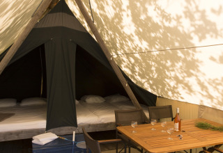 Interior view of a Canadienne safari tent at Village Huttopia Lac de Rillé, France, with table and beds.