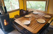 Mesa preparada para cuatro en tienda safari Trappeur con estufa de leña en Village Huttopia Lac de Rillé, Francia.