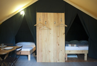 Interieur van de Trappeur safaritent in Village Huttopia Lac de Rillé, Frankrijk, met twee bedden en eetruimte.