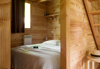 Chambre en bois avec lit à The Cabin Forest, Village Huttopia Lac de Rillé, France.